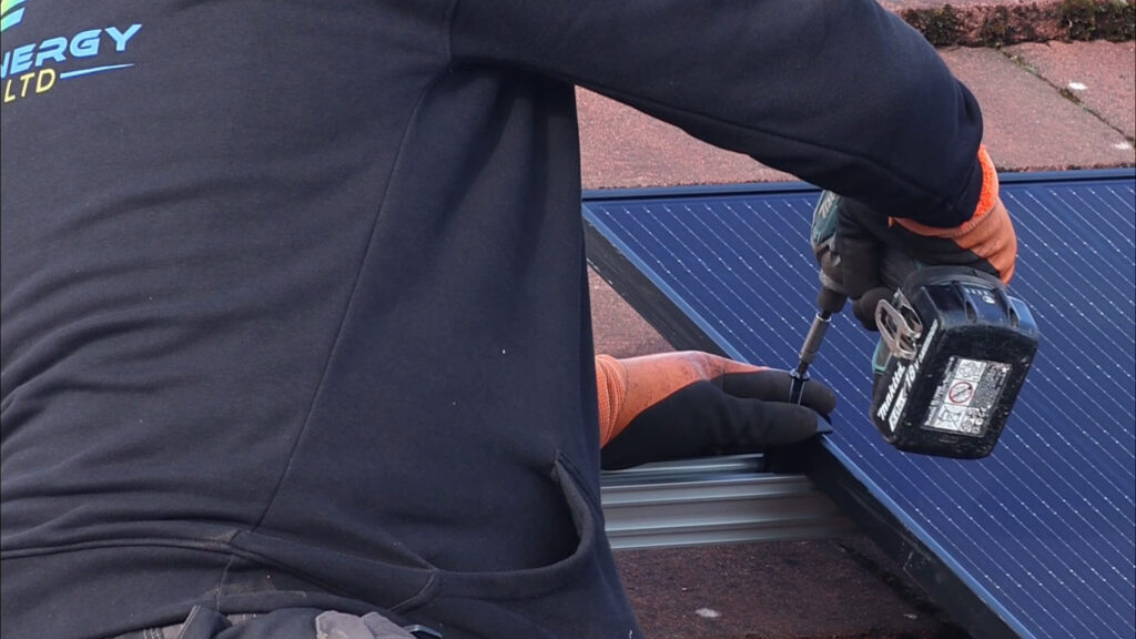 man screwing in a solar panel on a roof