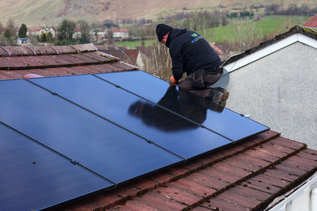 A man installing solar panels on a roof