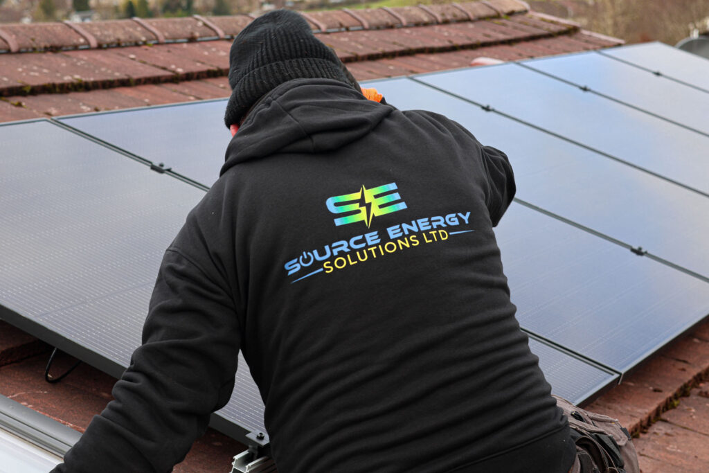 man on a roof with solar panels in the background