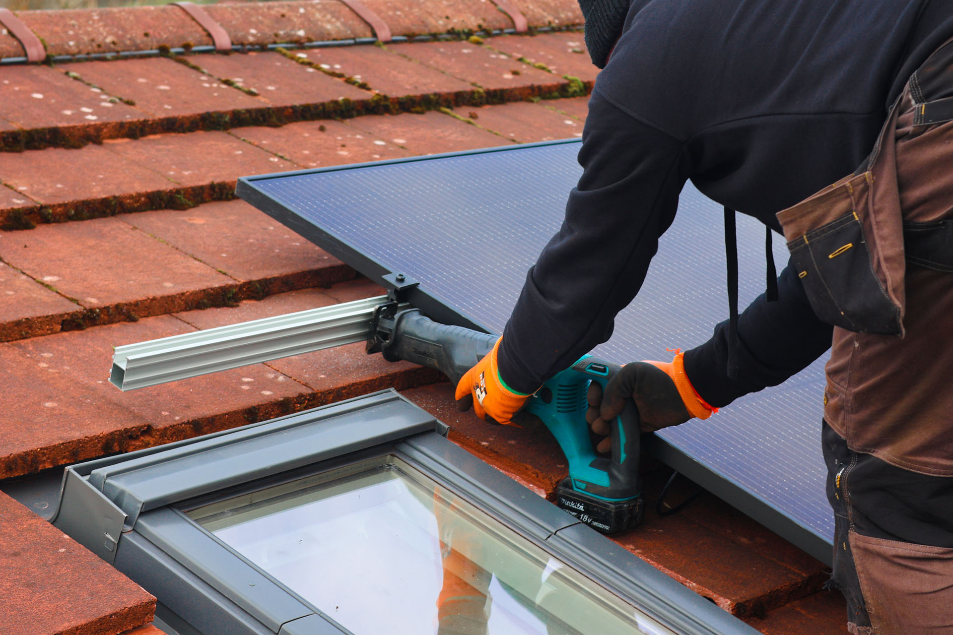 man installing a solar panel on a roof